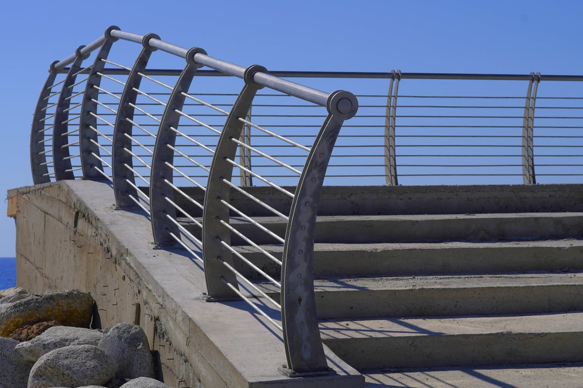 Contemporary curved stainless steel railings with clean lines against a clear blue sky
